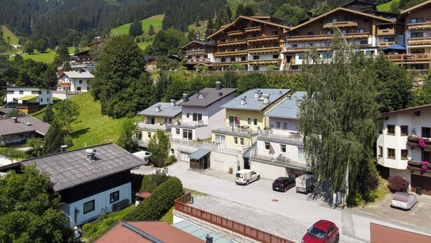 A mountain resort with chalet-style buildings, a paved road, and a parking area. - Apartment Summer & Winter Fun II (Zell am See)