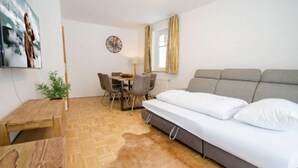 A room with a bed, a desk, a chair, a lamp, and a wall clock. - Apartment Summer & Winter Fun II (Zell am See)