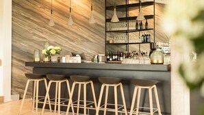 A modern bar area with a marble wall, pendant lighting, and a bar stocked with bottles. - Das ACKER Hotel (Neuburg)