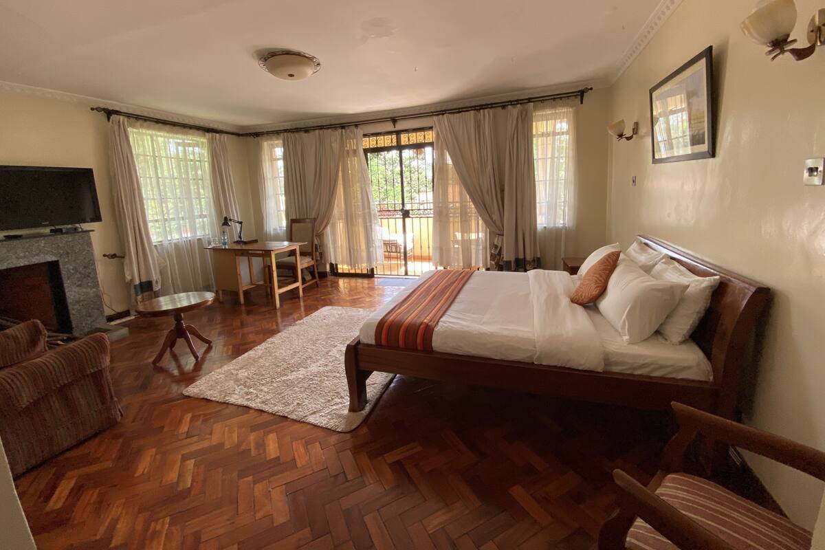 A spacious bedroom with a large bed, a desk, and a television.