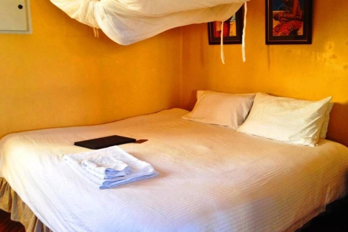 A bed with white bedding, a black book, and folded towels.