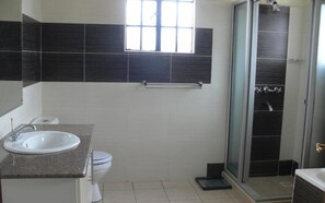 A bathroom with a sink, toilet, and a shower area. - Dreamplace Bed and Breakfast (Nairobi)