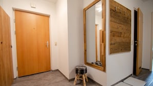 Un pasillo con una puerta de madera, un espejo grande y un revestimiento de madera en la pared.