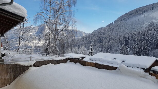Paisaje montañoso cubierto de nieve con una valla de madera y un edificio en primer plano.