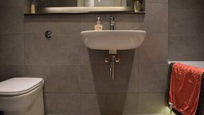 Ein Badezimmer mit Toilette, Waschbecken mit Seifenspender und Handtuchhalter mit einem roten Handtuch.