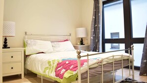 Ein Schlafzimmer mit Bett, Nachttischen und einem Fenster mit Vorhängen.