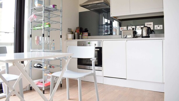 Eine moderne Küche mit weißen Schränken, einem Edelstahlbackofen und einer Kaffeemaschine auf der Arbeitsplatte.