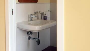 A bathroom with a white sink, a mirror above it, and a patterned mat on the floor.