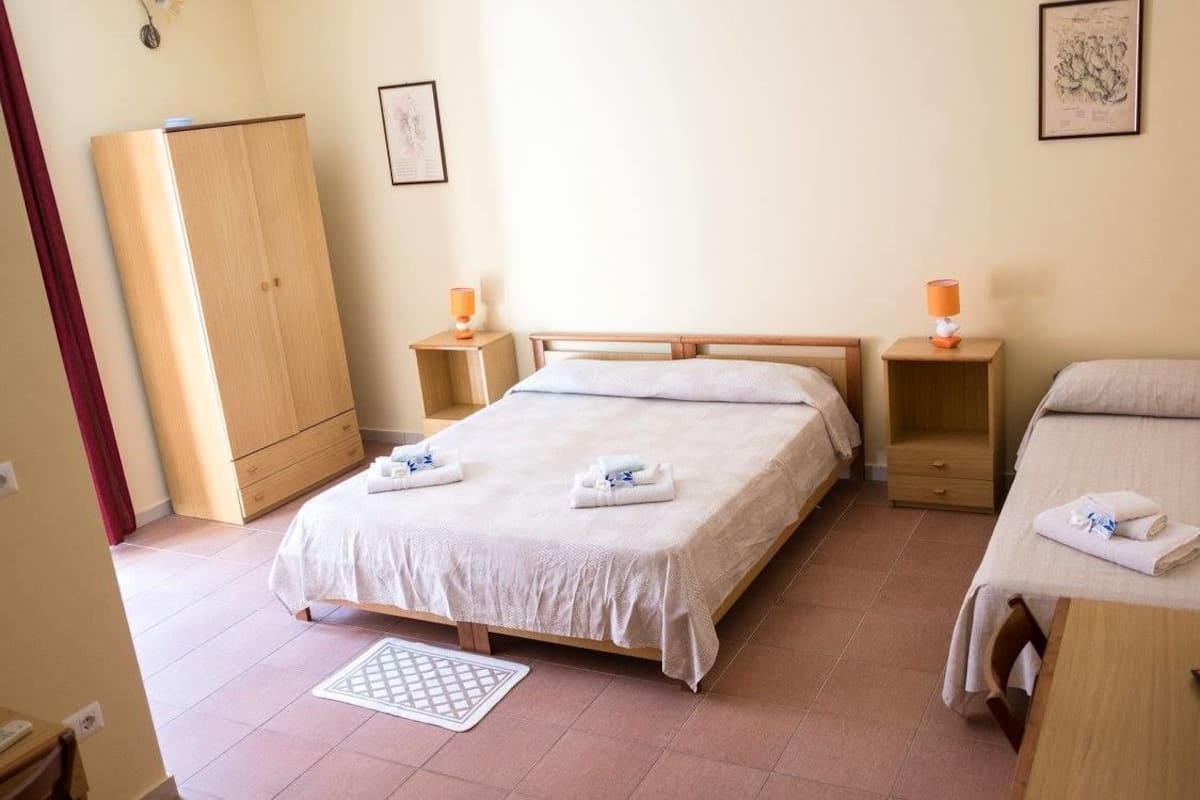 Una camera d'albergo con un letto grande, due comodini, un armadio e un piccolo tappeto.