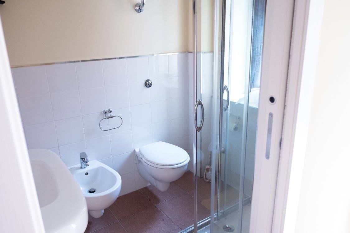 Un baño con bidé, inodoro y cabina de ducha de vidrio.