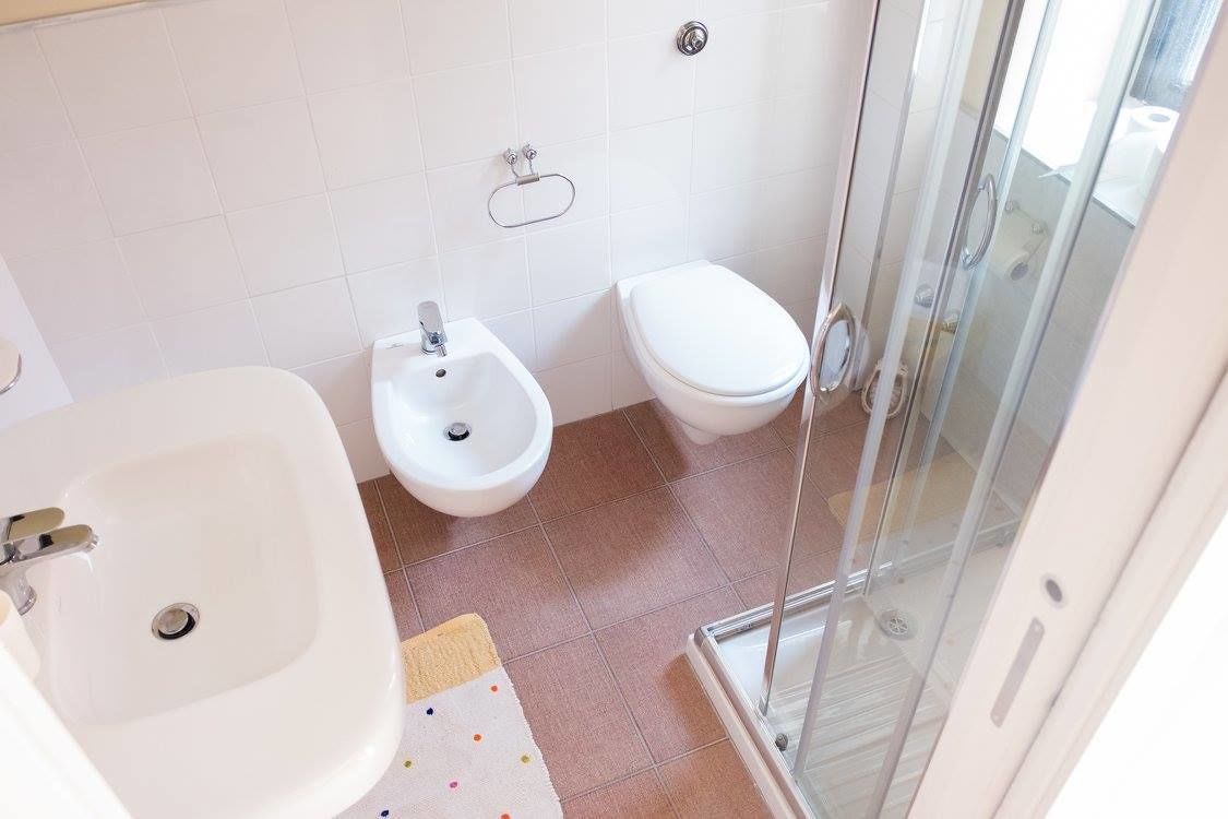A bathroom with a bidet, toilet, and a glass-enclosed shower.