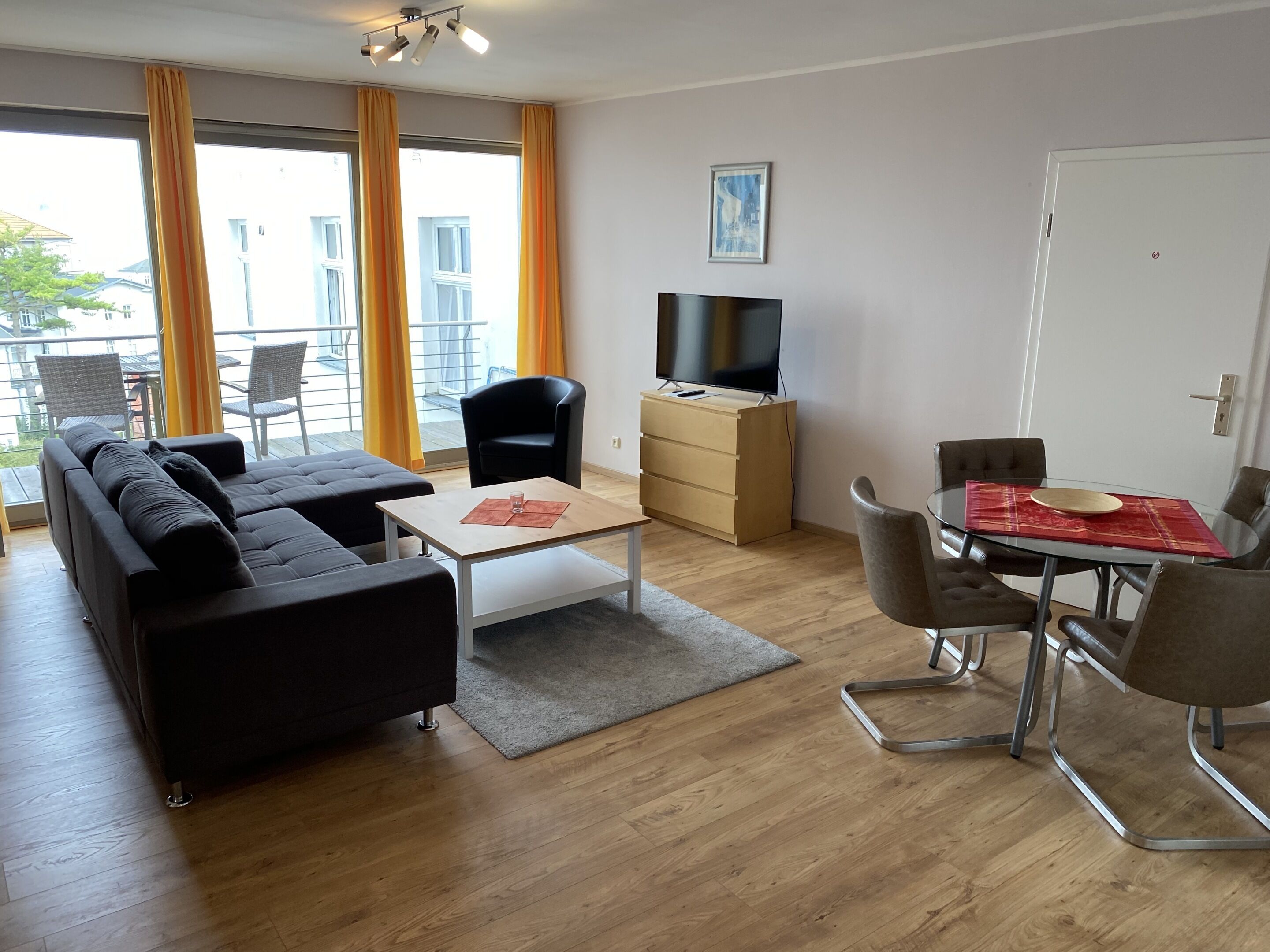 Una sala de estar moderna con un sofá, una mesa de centro, un televisor y un comedor con sillas y una mesa.
