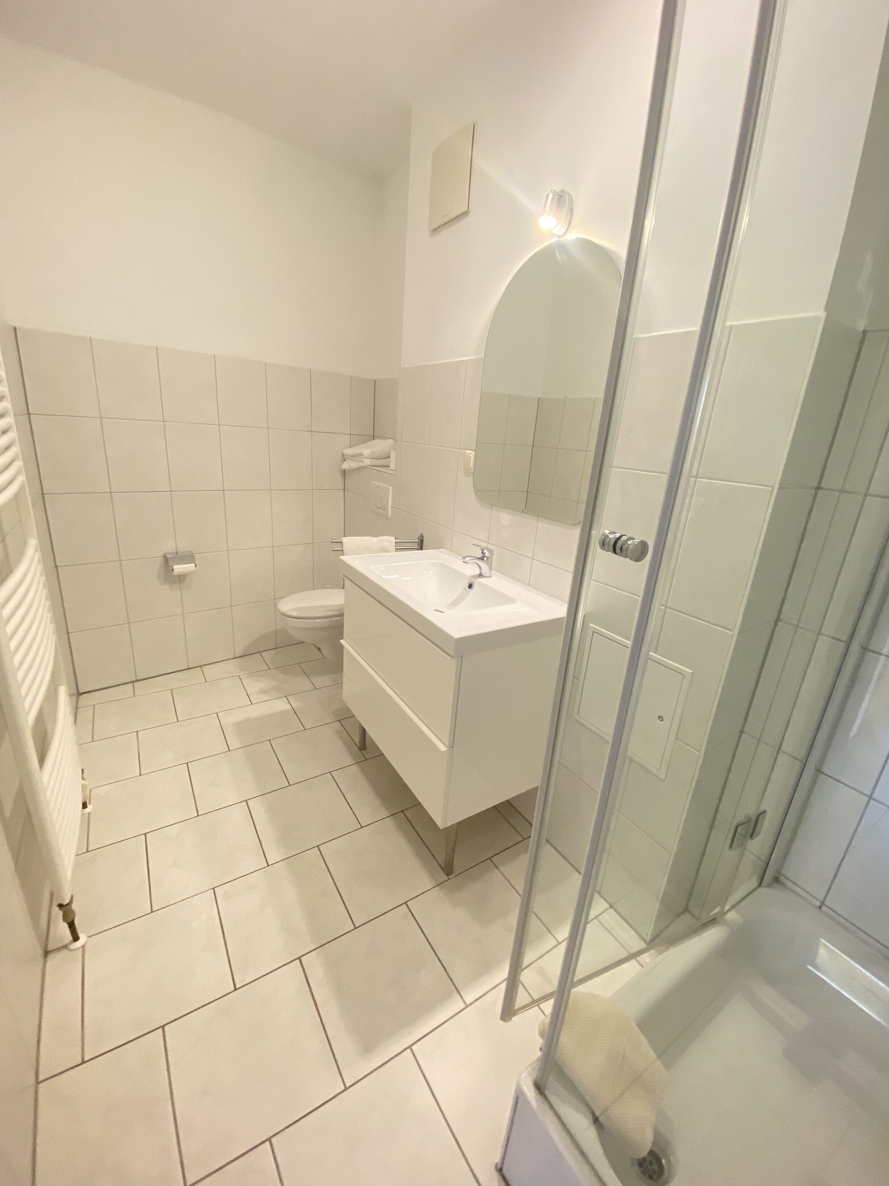 Ein modernes Badezimmer mit Waschbecken, Spiegel und Toilette in Weiß.