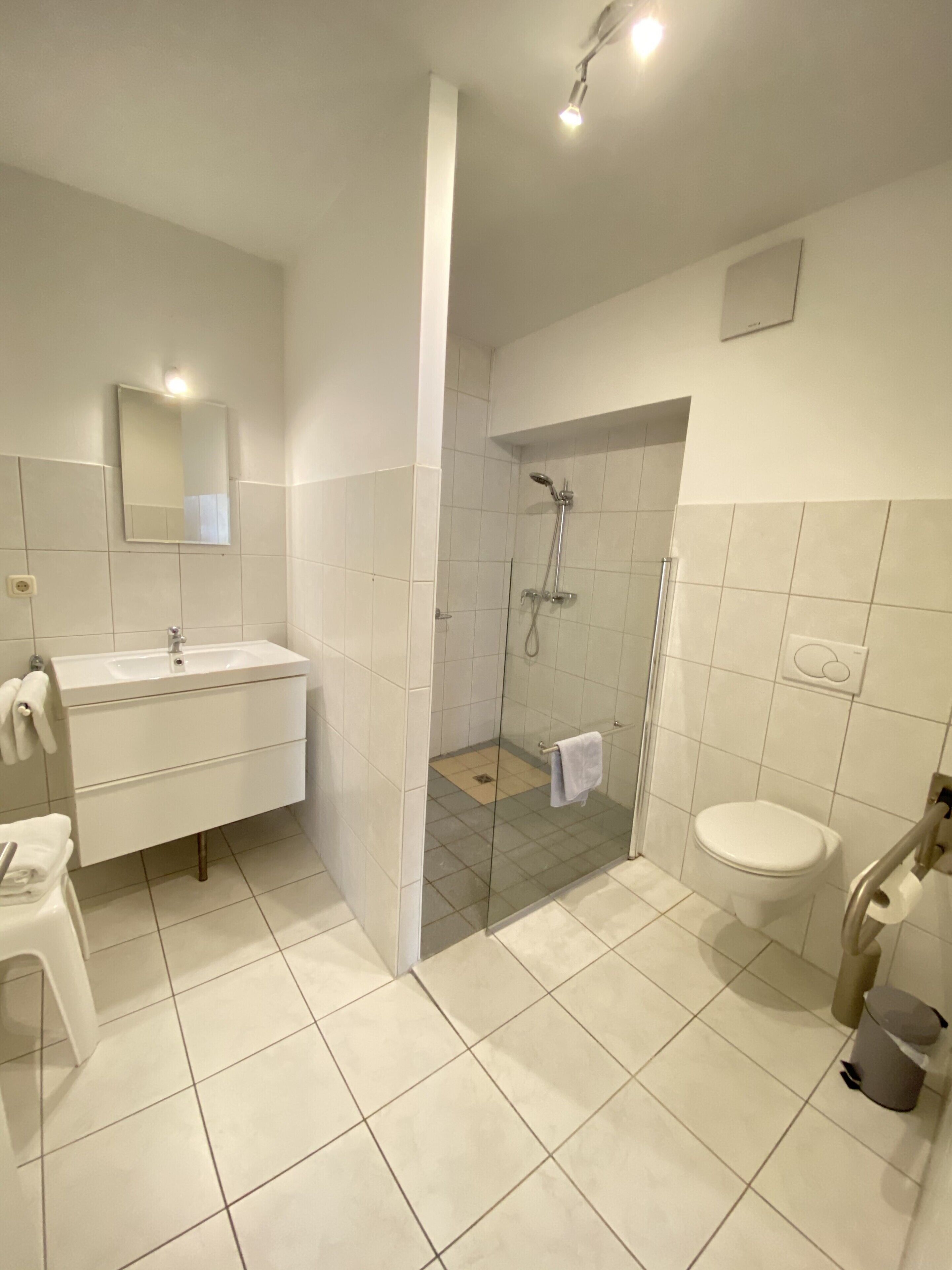 A modern bathroom with a white sink, mirror, and toilet.