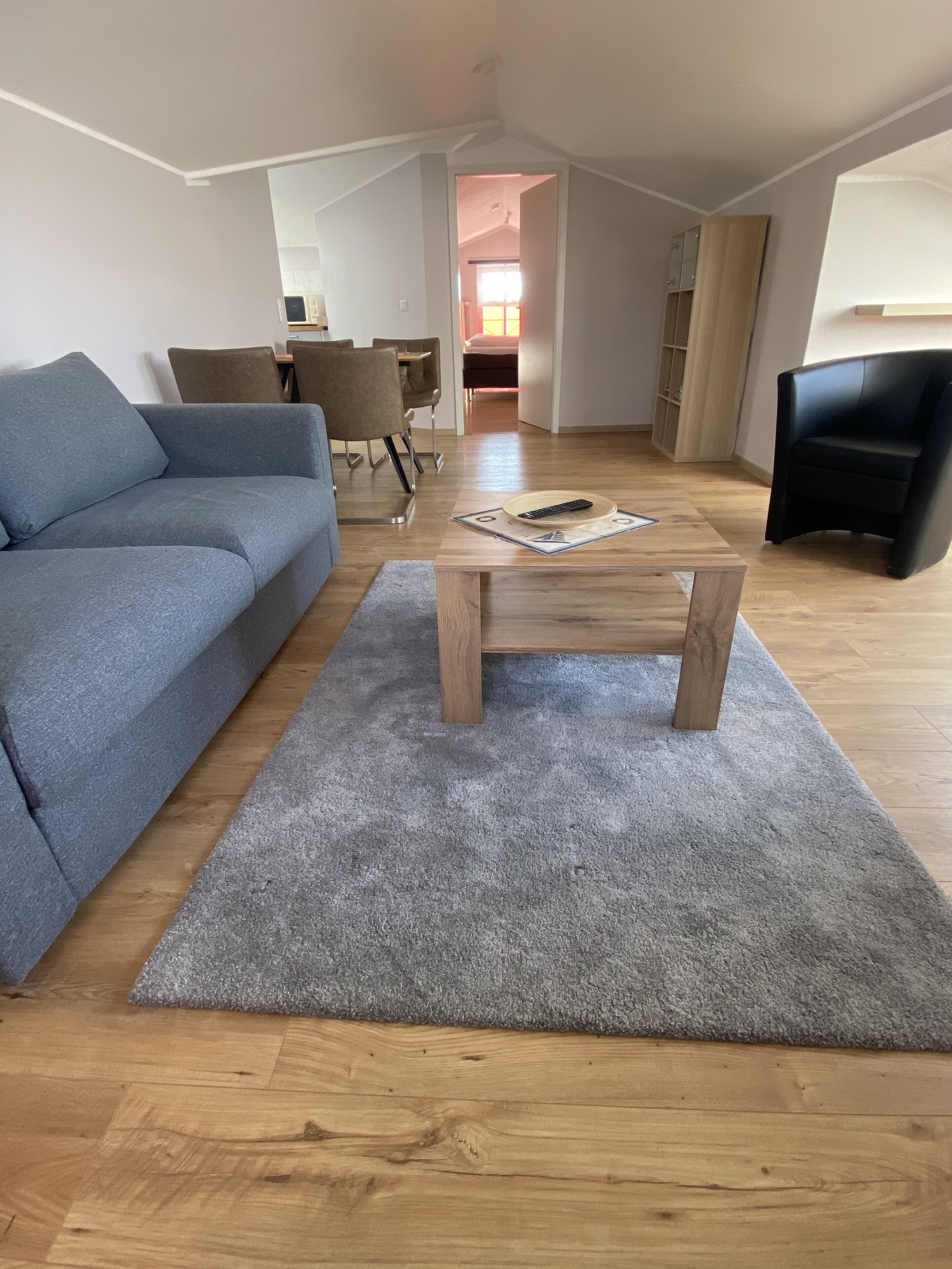 A modern living room with a grey sofa, a wooden coffee table, and a grey rug.