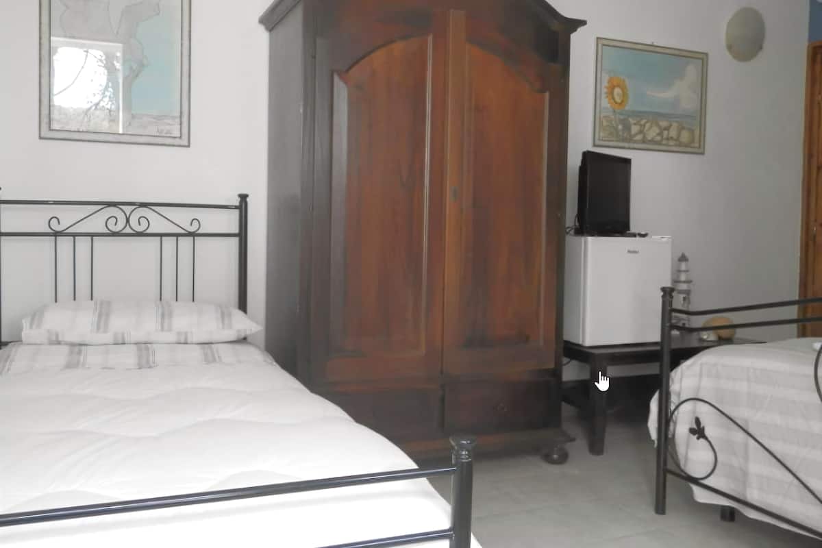 A bedroom with two beds, a wardrobe, a television, and a small table.