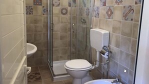 Et badeværelse med bruser, toilet og håndvask.