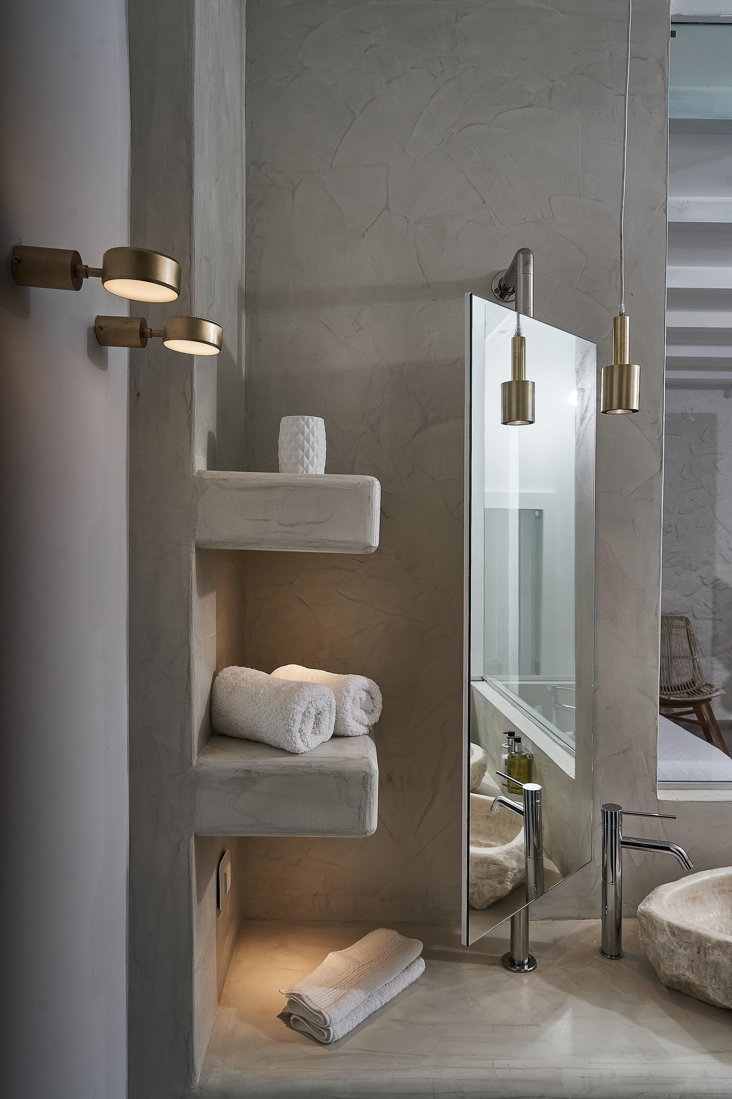 A modern bathroom with a large mirror, a freestanding sink, and built-in shelves holding towels.