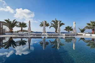 Una piscina al aire libre, sombrillas, sillones reclinables de piscina
