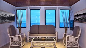A room with a sofa, two chairs, a coffee table, and large windows with a view of the sea. - Jungle Experiences La Perla (Nauta)