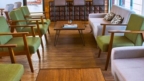 A modern interior with a wooden coffee table, green and beige chairs, a sofa, and a bar area with bottles. - Jungle Experiences La Perla (Nauta)