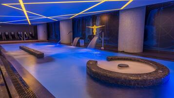 Relax in a serene spa area with a large hot tub, surrounded by a geometric-patterned ceiling and comfortable seating.