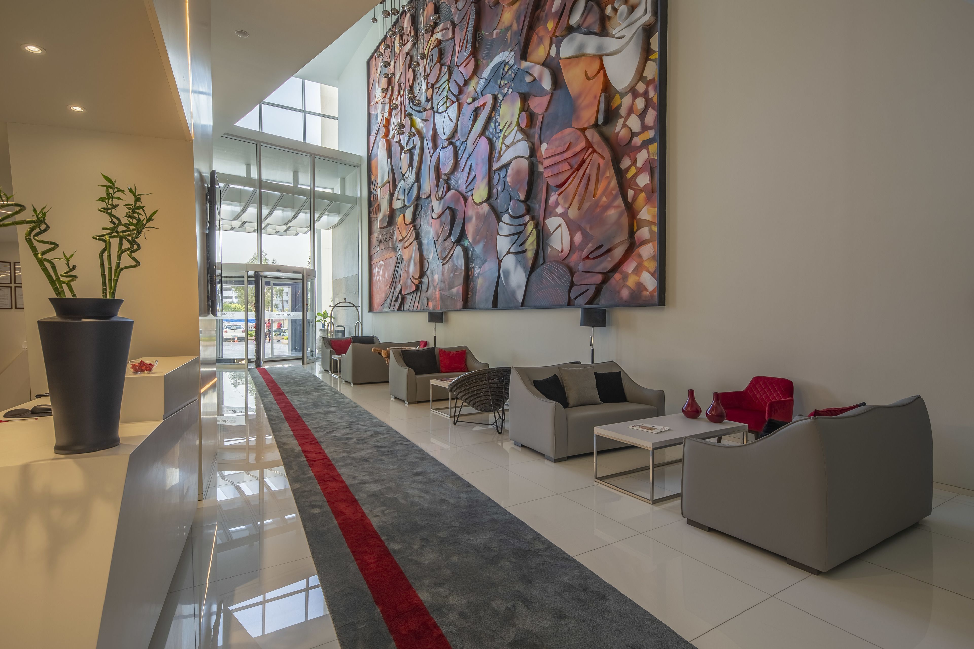 Eine moderne Lobby mit rotem Teppich, zeitgemäßen Sofas und einem großen abstrakten Gemälde.