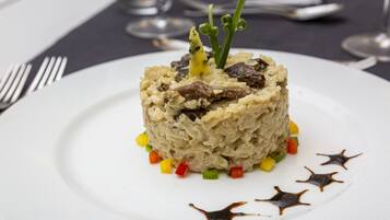 A plated dish with a garnish, surrounded by colorful diced vegetables and a dark sauce on a white plate.