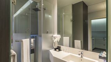 A modern bathroom with a glass shower enclosure, a large mirror, and a white sink.