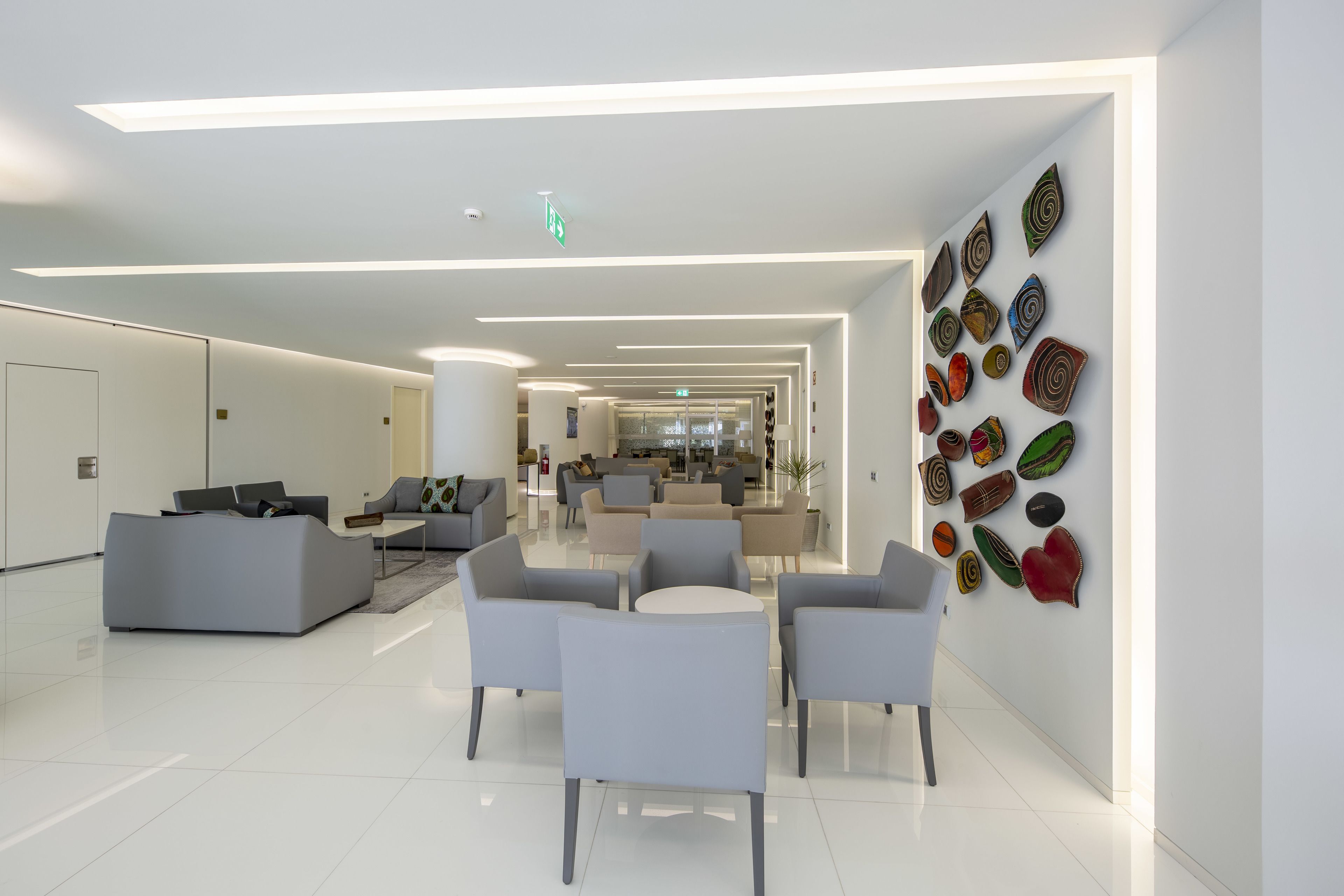 A modern lobby with a central seating area, a reception desk, and a wall with colorful artwork.