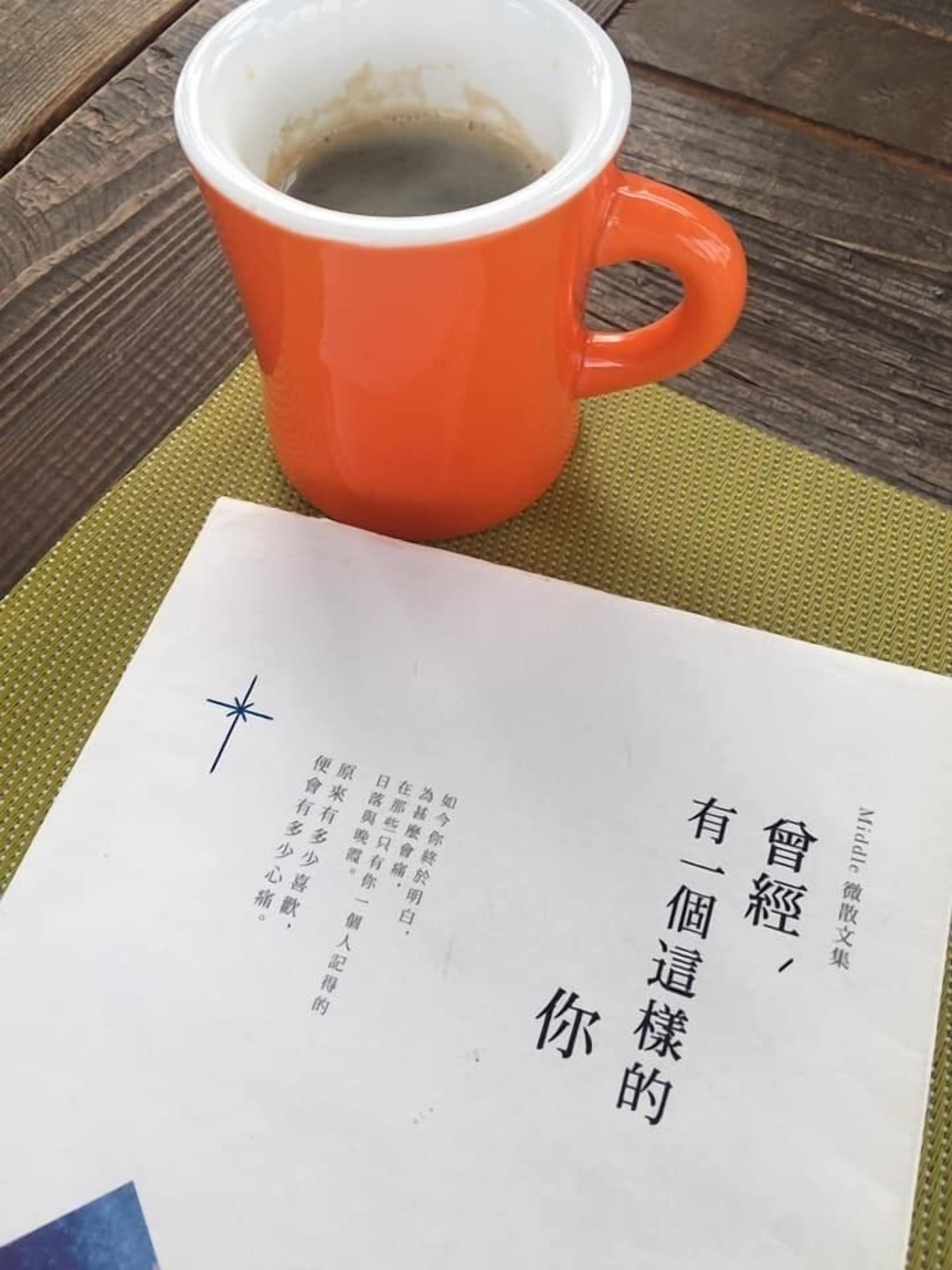 A table with a red mug and a piece of paper with Chinese characters.