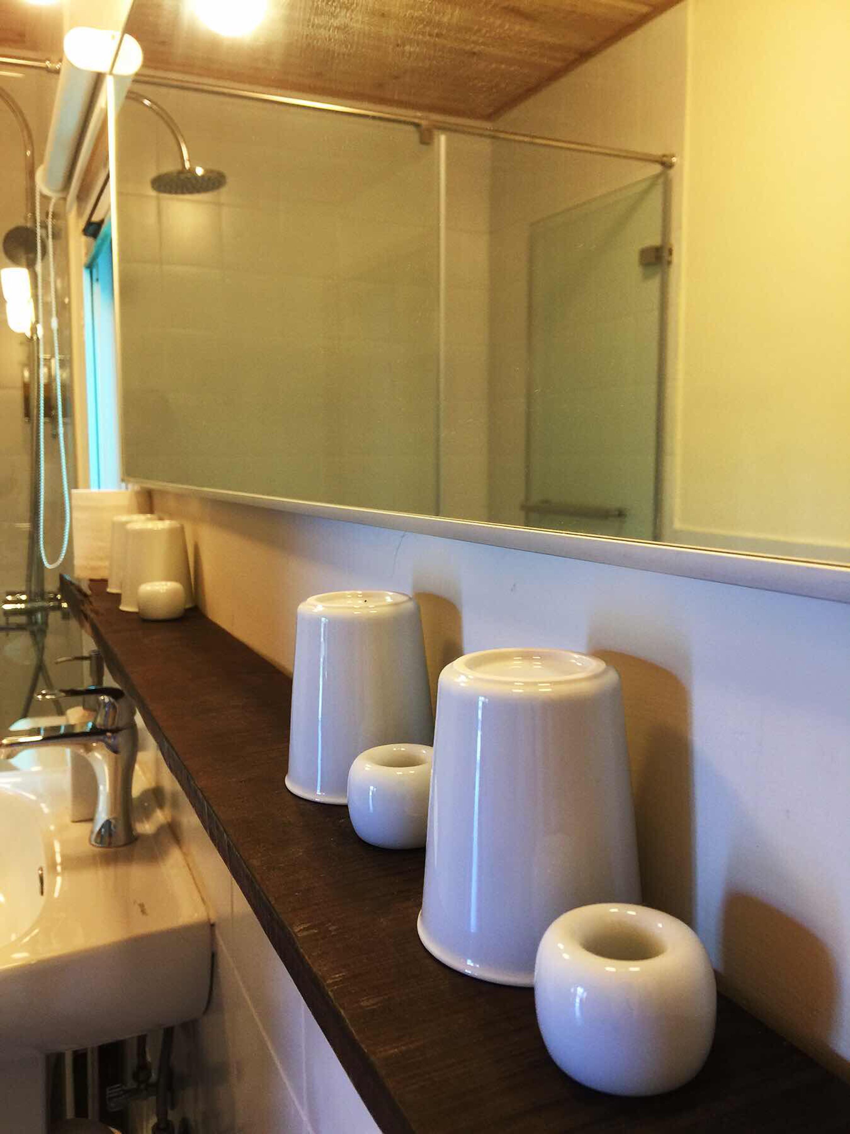 A bathroom with a large mirror, a sink, and three white soap dispensers on the counter.