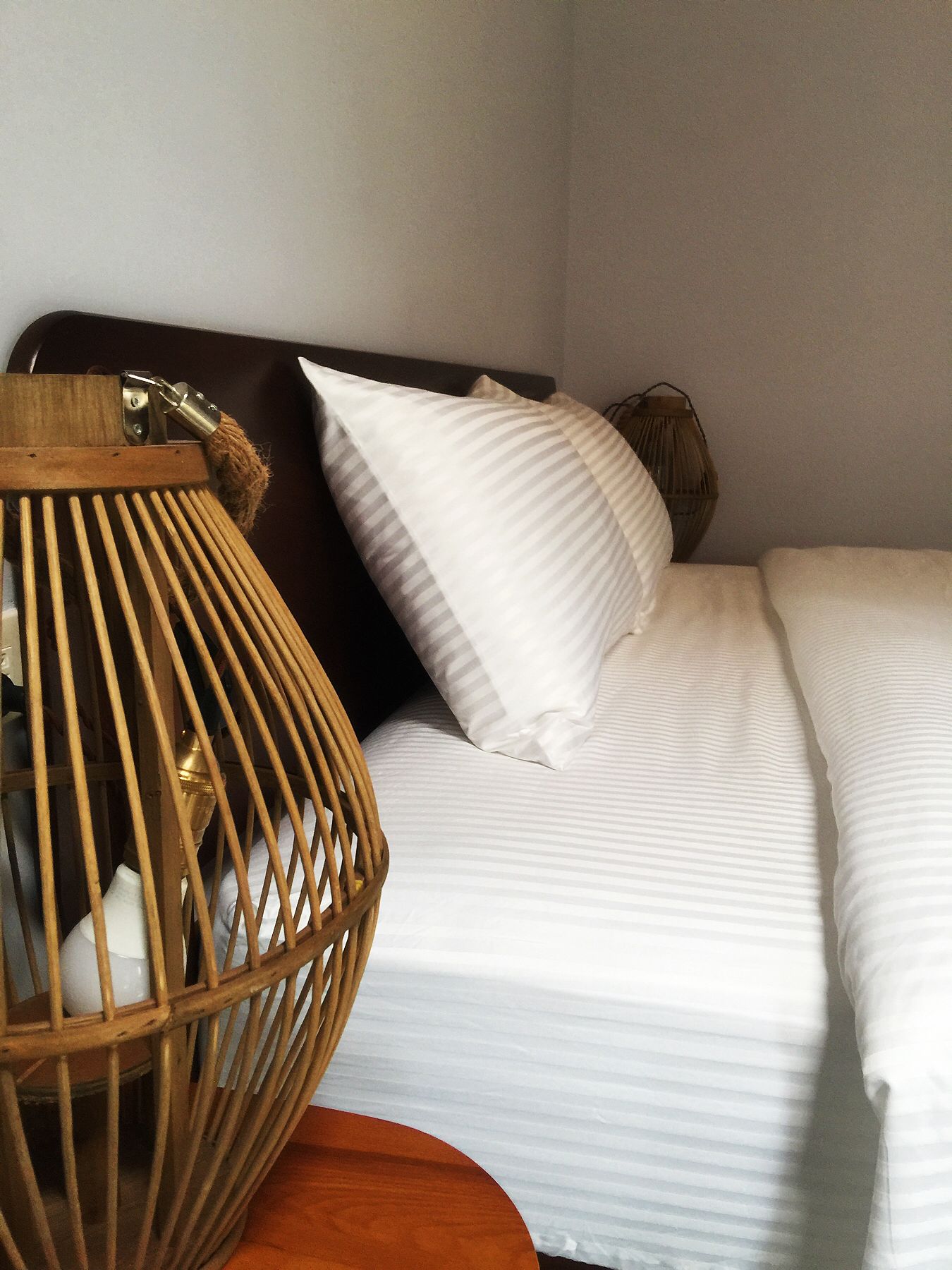 Una cama con ropa de cama blanca y cabecera de madera.