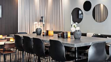 Un comedor moderno con una mesa larga, sillas negras, velas y un florero con flores.