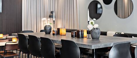 Un comedor moderno con una mesa larga, sillas negras, velas y un florero con flores.