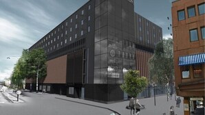 Moderni hotelli, jossa on tumma julkisivu, useita kerroksia ja huomiota herättävä kyltti.