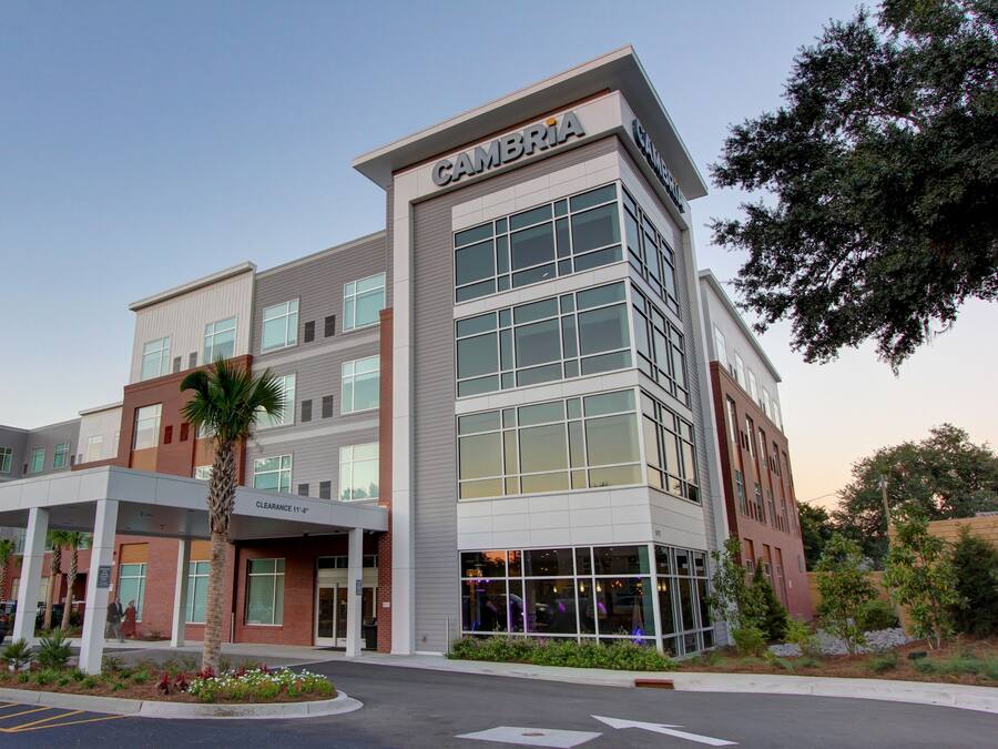A multi-story building with a prominent 'CAMBRIA' sign, featuring a modern architectural design with large windows and a covered entrance area.