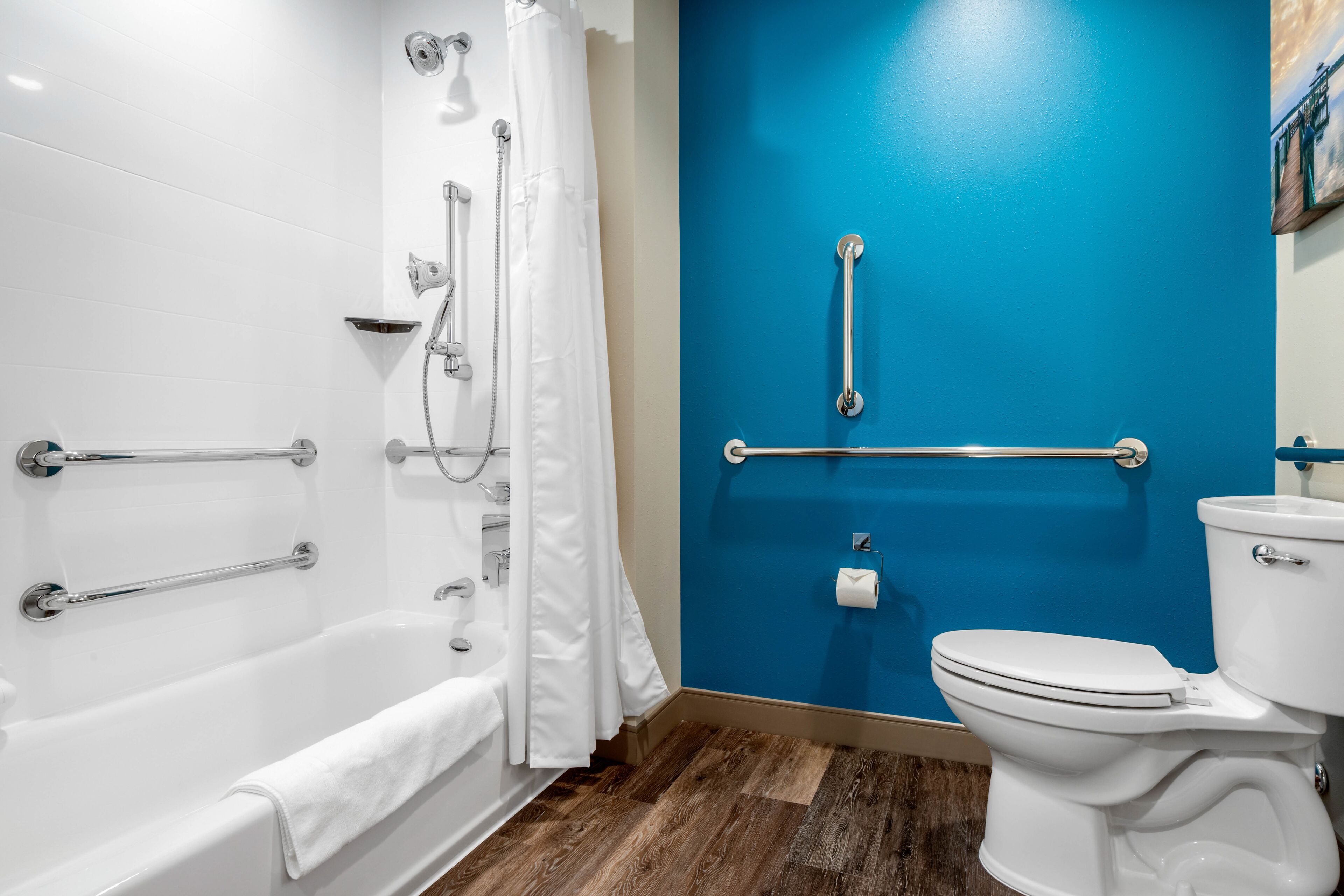 A bathroom with a white bathtub, a white toilet, and a blue wall.