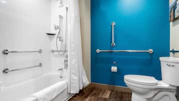 A bathroom with a white bathtub, a white toilet, and a blue wall.