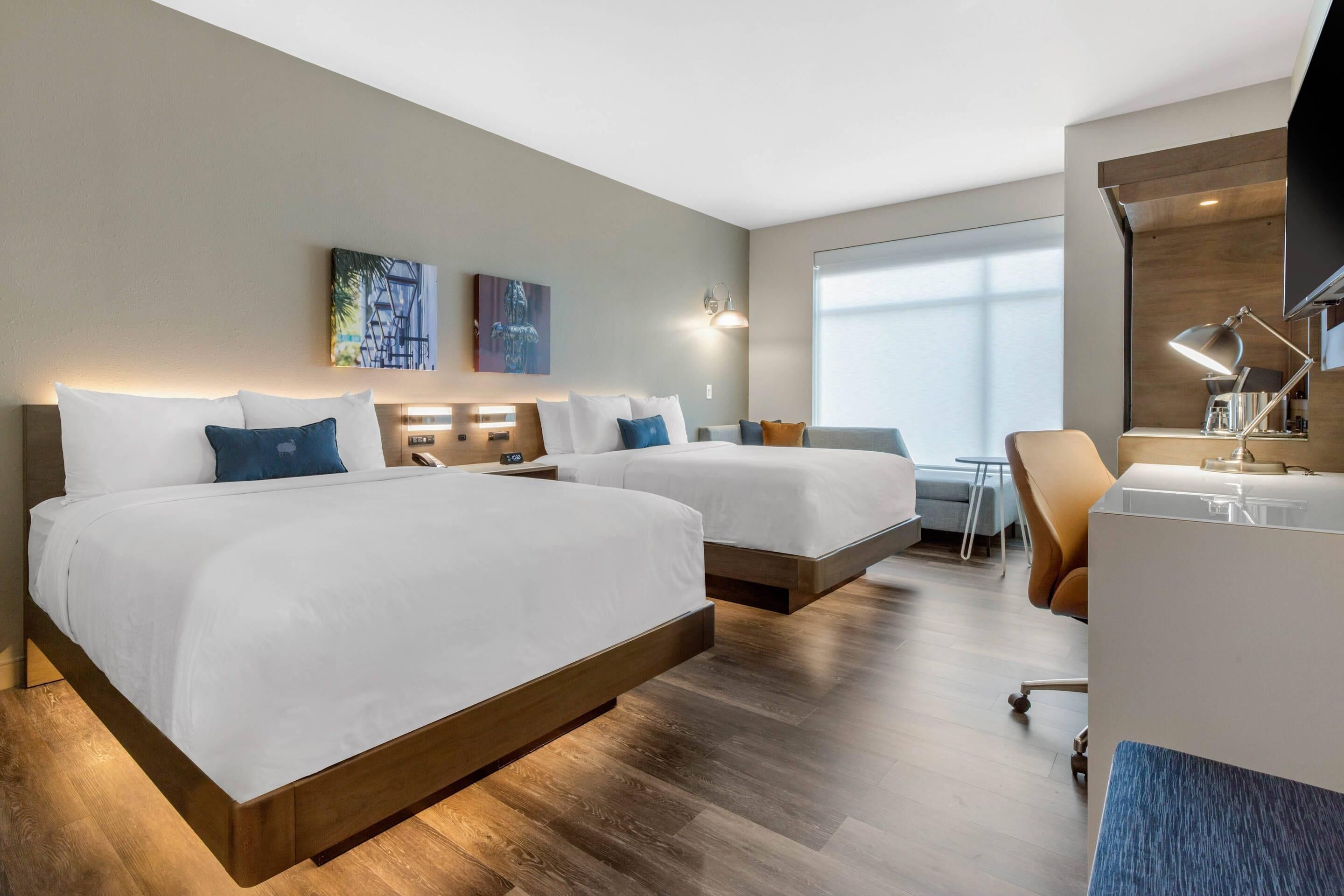 Une chambre d’hôtel avec deux lits, un bureau et une chaise.