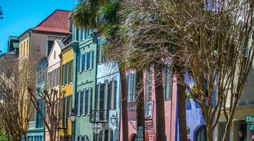 Uma fileira de edifícios coloridos com uma variedade de estilos arquitetônicos, incluindo um edifício com telhado vermelho e outro com fachada verde.