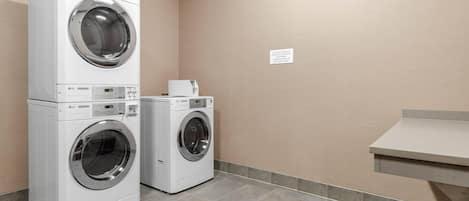 Een wasserette met twee gestapelde voorladers en één wandmodel wasmachine.