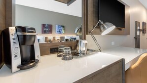 Une cuisine moderne équipée d’une machine à café Keurig, d’un espace dédié au café, d’un grand miroir et d’œuvres d’art accrochées au mur.