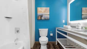 Un baño con inodoro y lavamanos blancos, y suelo de madera.