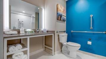 A modern bathroom with a white toilet, a sink with a mirror, and a blue accent wall.