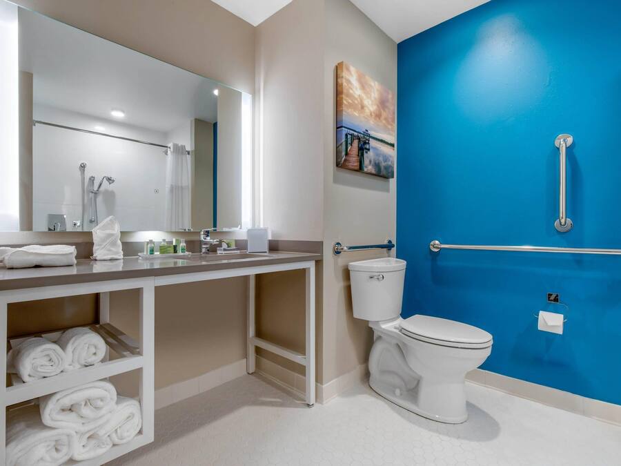 A modern bathroom with a white toilet, a sink with a mirror, and a blue accent wall.