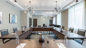 Un salón de conferencias con una larga mesa, sillas, una cafetera y un candelabro.