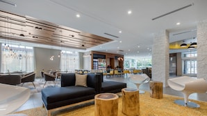 Un espace de détente moderne avec un canapé noir, des tabourets en bois et des fauteuils contemporains.