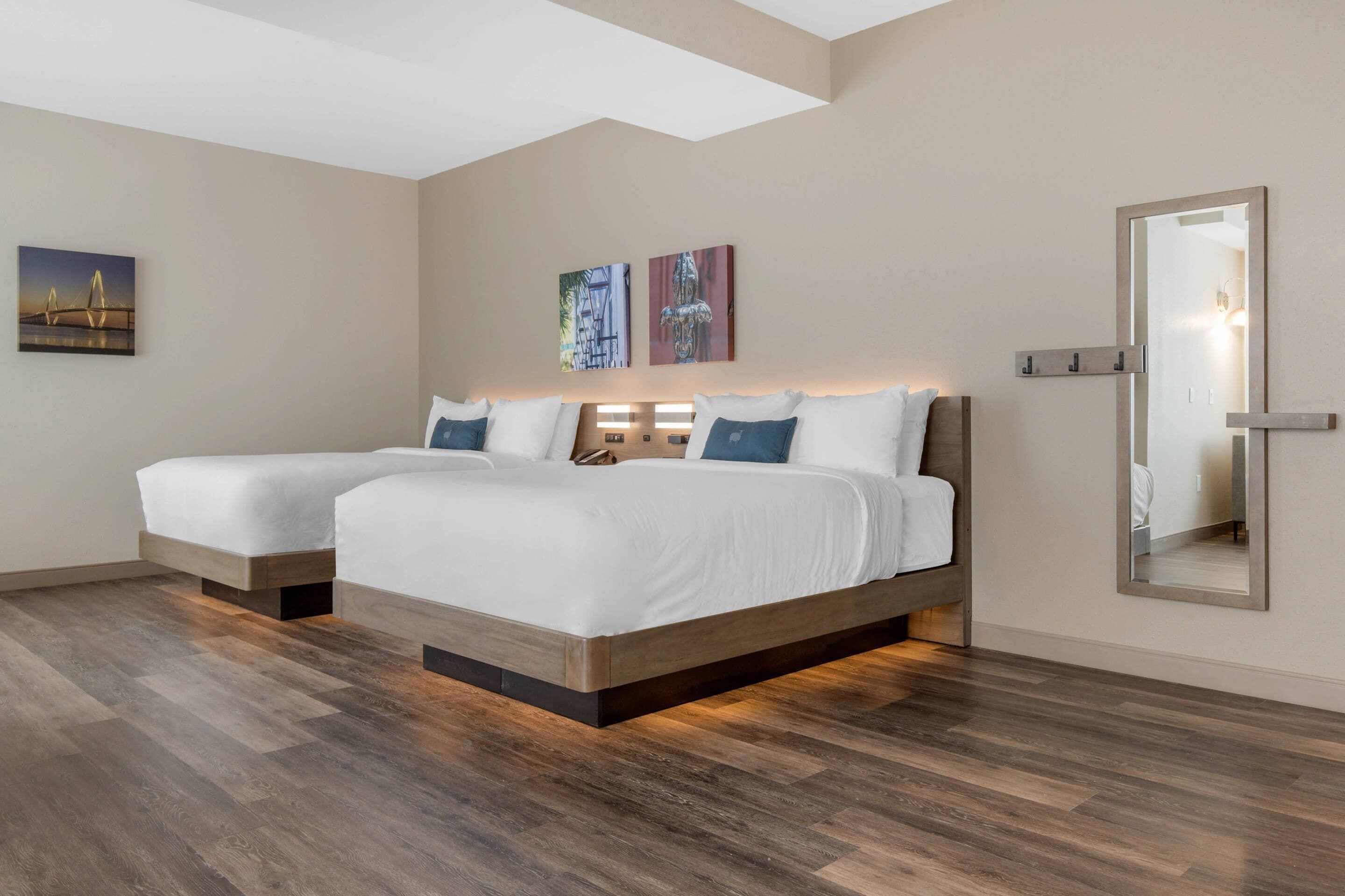 Una habitación de hotel moderna con dos camas, un espejo grande y obras de arte en las paredes.