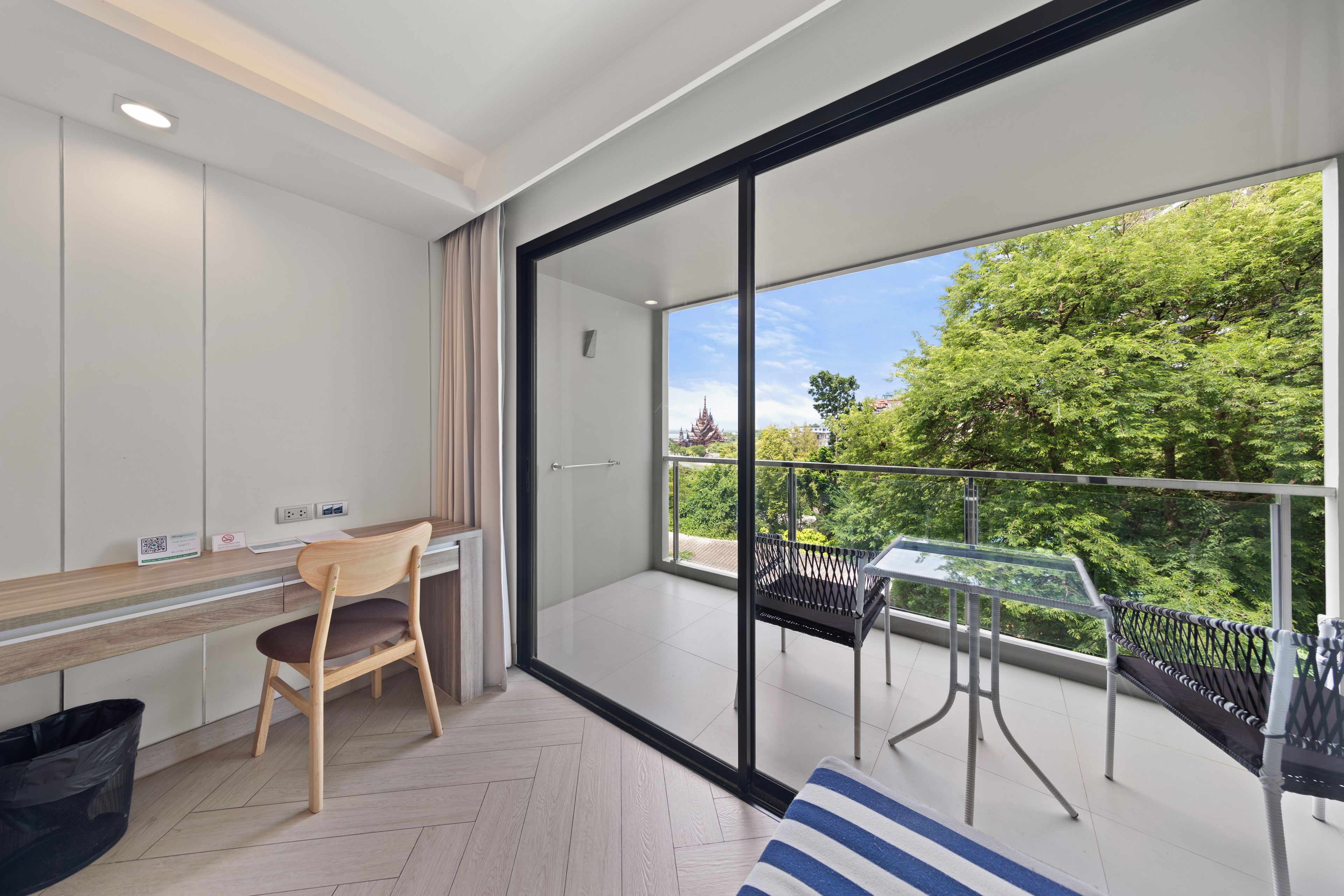 Een moderne kamer met balkon, bureau en stoel.